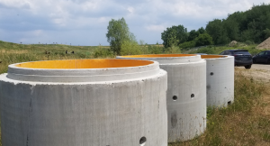 3 concrete pipes sitting on grass at job site.